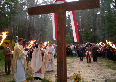 Ks. Leszek Tokarzewski poświęca krzyż na grobie Polaków